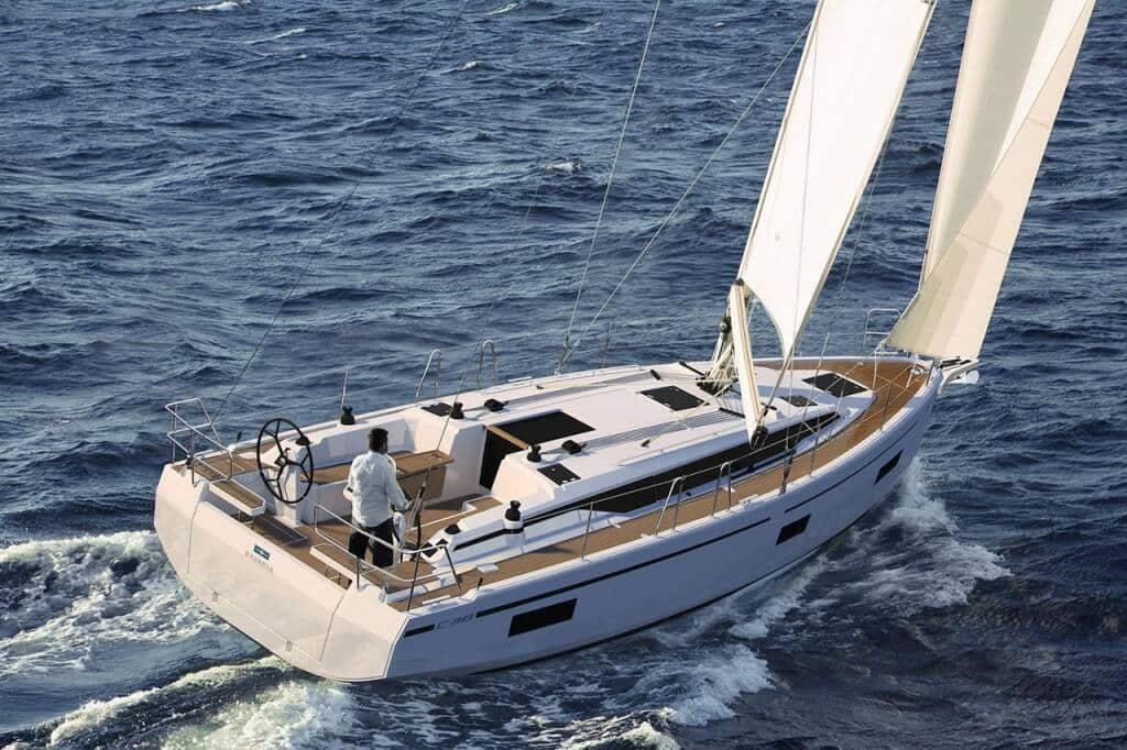 A 38 ft cruising yacht under full sail, skipper at the wheel