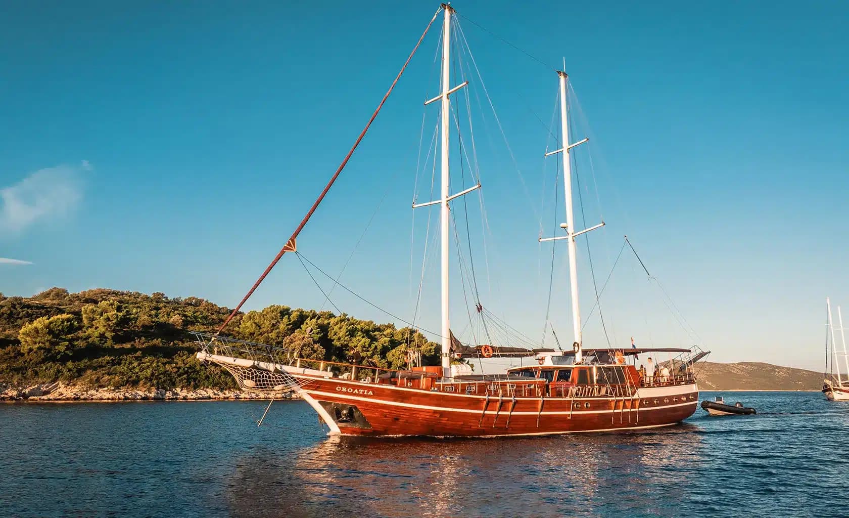 A classic two-masted wooden gulet at anchor in a Croatian bay