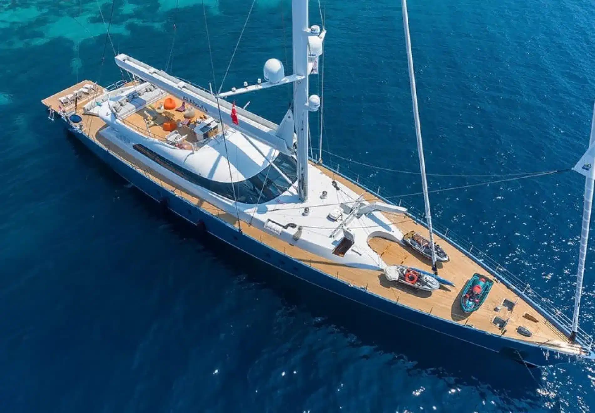 A large luxury sailing yacht seen from above, its deck laid out for guests
