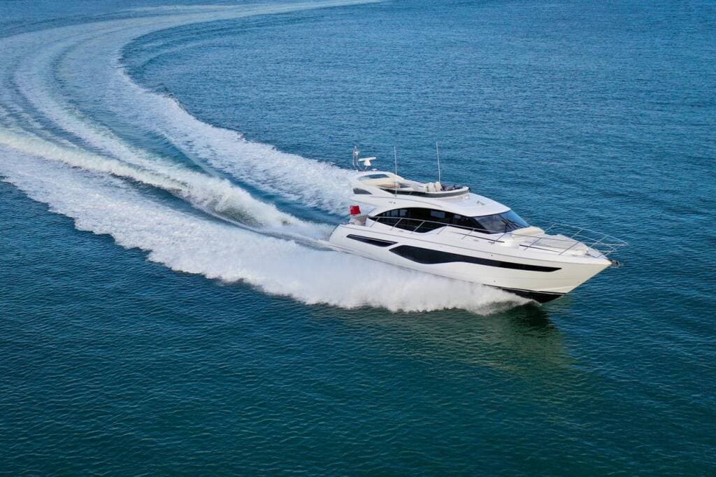 A flybridge motor yacht at speed, leaving a curving wake