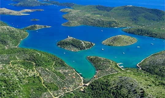 Aerial view of Telašćica bay on Dugi otok, with yachts anchored between wooded islets and clear turquoise shallows